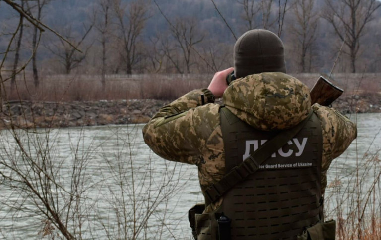 На заглавном фото: Украинский пограничник высматривает тех, кто пытается сбежать от мобилизации через Тису...