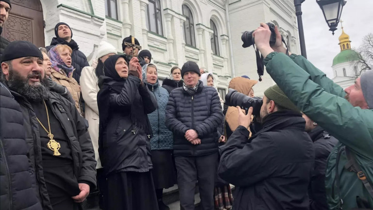 На заглавном фото: Защитники Киево-Печерской лавры декламируют  Евангелие от Матфея у одного из лаврских храмов, 2023 год. Источник фото – пресс-служба УПЦ