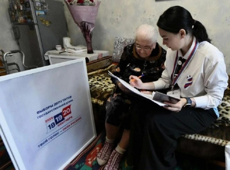 На заглавном фото: 100-летняя жительница Донецка Мария Слута вместе с представителем избирательной комиссии. Сначала, как положено, проверка документов (источник – ZOV Славянск).